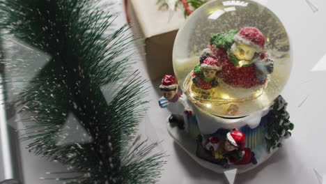 Animation-of-snow-falling-over-christmas-snow-globe-and-decorations