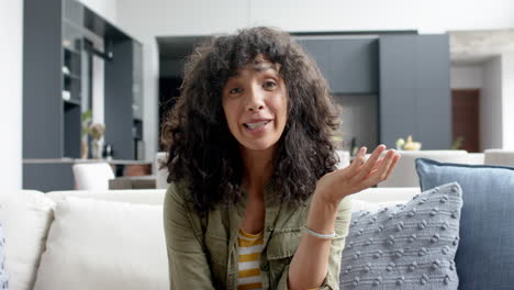 Portrait-of-happy-biracial-woman-sitting-on-couch-and-having-video-call-at-home,-slow-motion