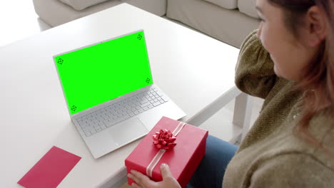Kaukasische-Frau-Hält-Rotes-Geschenk-Mit-Laptop-Und-Leerem-Platz-Auf-Grünem-Bildschirm