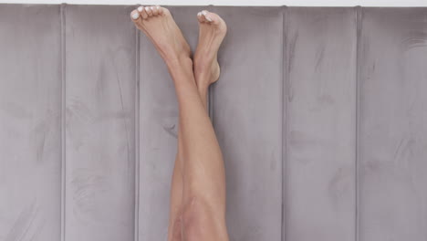 Close-up-of-legs-of-biracial-woman-lying-on-bed-at-home,-slow-motion