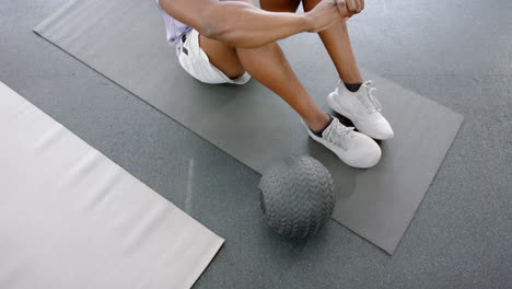 Fit-African-American-man-resting-after-workout-at-the-gym-with-a-medicine-ball