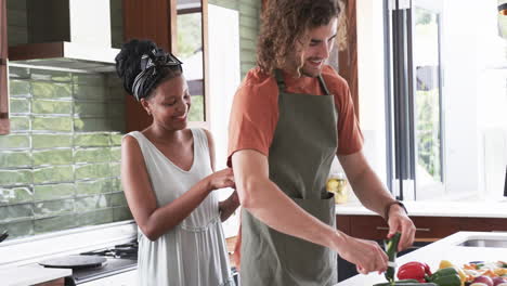 Diverse-couple,-a-young-African-American-woman-and-a-young-Caucasian-man,-cooking-together-at-home