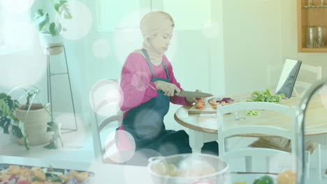 Mujer-Birracial-Con-Hijab-Cortando-Verduras-En-La-Cocina,-Cocinando-Sobre-Puntos-De-Luz