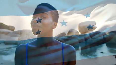 Animation-of-honduran-flag-over-happy-african-american-woman-on-sunny-beach