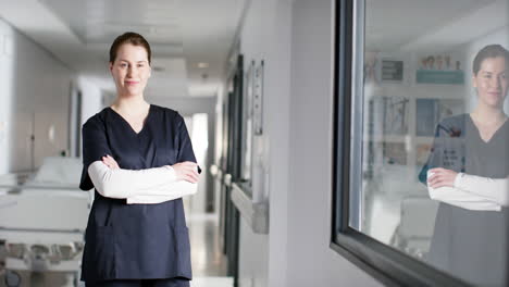 Portrait-of-happy-caucasian-female-doctor-wearing-scrubs-in-hospital,-copy-space,-slow-motion