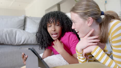 Happy-diverse-teenage-female-friends-talking-and-using-tablet-at-home,-slow-motion