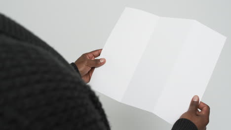 Video-of-hands-of-african-american-man-holding-blank-page,-copy-space-on-white-background