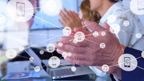 Animation-of-network-of-connections-with-icons-over-diverse-business-people-clapping-hands