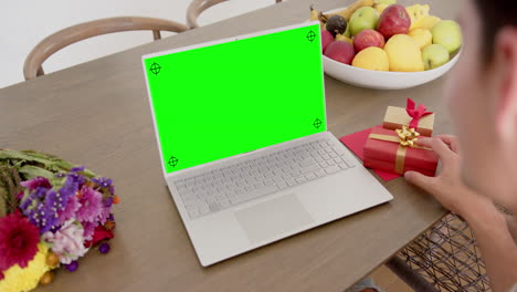 Mujer-Caucásica-Sosteniendo-Un-Regalo-Rojo-Usando-Una-Computadora-Portátil-Con-Espacio-Para-Copiar-En-Pantalla-Verde