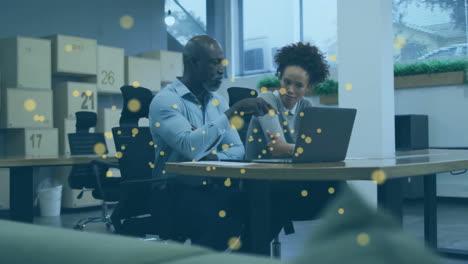 Animation-of-glowing-yellow-spots-over-diverse-business-people-in-office