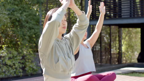Fokussierte-Asiatische-Freundinnen-Praktizieren-Yoga-Meditation-Auf-Sonniger-Terrasse,-Zeitlupe