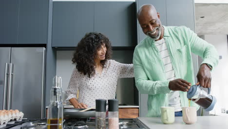 Happy-biracial-couple-embracing-and-pouring-coffee-in-kitchen,-slow-motion