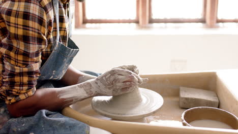 African-american-male-potter-using-potter's-wheel-in-pottery-studio,-slow-motion