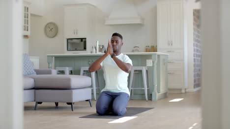 Focused-african-american-man-practising-yoga-meditation-in-sunny-living-room,-slow-motion