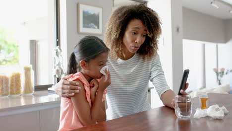 Worried-biracial-mother-and-sick-daughter-having-smartphone-video-call-with-doctor,-slow-motion