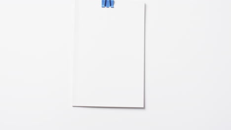 Video-of-book-with-white-blank-pages-and-copy-space-hanging-on-clip-on-white-background