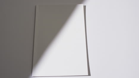 Video-Von-Schatten-über-Einem-Buch-Mit-Leeren-Weißen-Seiten-Und-Platz-Zum-Kopieren-Auf-Weißem-Hintergrund