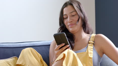 Glückliches-Biracial-Teenager-Mädchen,-Das-Auf-Der-Couch-Sitzt-Und-Kreditkarte-Und-Smartphone-Online-Nutzt,-Zeitlupe