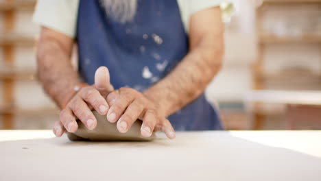 Hands-of-biracial-potter-with-long-beard-shaping-clay-with-hands-in-pottery-studio,-slow-motion