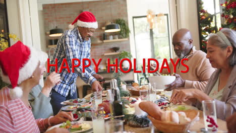 Animation-of-happy-holidays-text-over-diverse-senior-friends-at-christmas-dinner-at-home