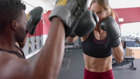 A-fit-young-Caucasian-woman-and-an-African-American-man-engage-in-boxing-training-at-the-gym