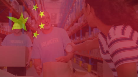 Animation-of-flag-of-china-over-diverse-male-volunteers-and-woman-making-donation-in-warehouse