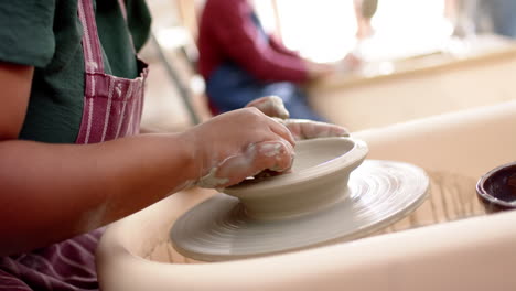 African-american-female-potter-using-potter's-wheel-in-pottery-studio,-slow-motion