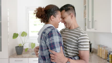 Happy-diverse-gay-male-couple-embracing-and-slow-dancing-in-kitchen,-slow-motion