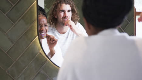 Diverse-couple,-a-young-African-American-woman-and-a-young-Caucasian-man,-brush-their-teeth-together