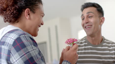 Romantic-diverse-gay-male-couple-giving-flower-and-embracing-in-living-room,-slow-motion