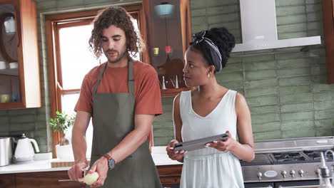 Diverse-couple,-a-young-African-American-woman-and-Caucasian-man,-cooking-in-a-home-kitchen