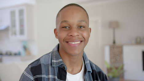 Portrait-of-happy-african-american-male-teenager-with-short-hair-at-home,-slow-motion