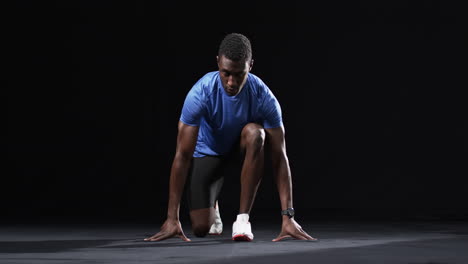 African-American-man-in-starting-position-for-a-sprint-on-a-black-background