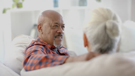 Glückliches-älteres,-Gemischtrassiges-Paar,-Das-Zu-Hause-Auf-Der-Couch-Sitzt-Und-Redet,-Zeitlupe