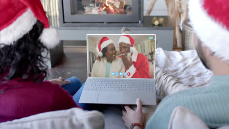 Happy-diverse-couple-and-senior-parents-having-christmas-laptop-video-call,-slow-motion