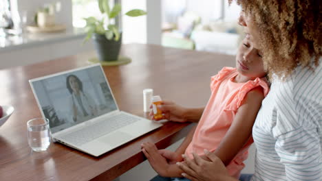 Biracial-mother-and-sick-daughter-having-laptop-video-call-with-female-doctor,-slow-motion