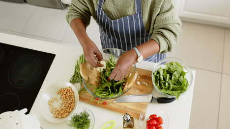 Afroamerikanische-Seniorin-Bereitet-Salat-In-Sonniger-Küche-Zu,-Zeitlupe