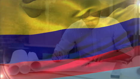 Animation-of-flag-of-colombia-waving-over-smiling-caucasian-male-architect-working-on-blueprint