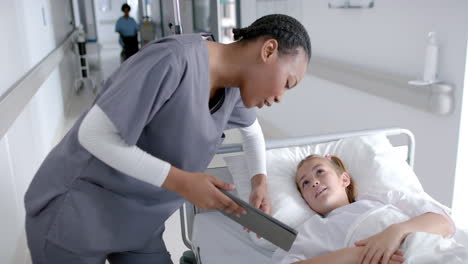 African-American-nurse-assists-a-Caucasian-girl-in-a-hospital,-with-copy-space