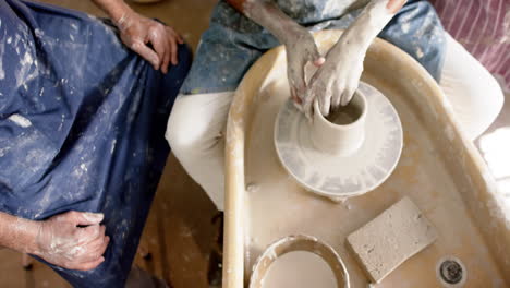 Hands-of-diverse-male-potters-using-potter's-wheel-in-pottery-studio,-slow-motion
