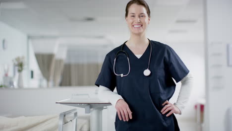 Portrait-of-happy-caucasian-female-doctor-wearing-scrubs-in-hospital,-copy-space,-slow-motion