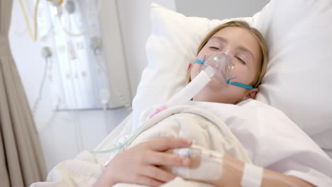 Caucasian-girl-patient-with-oxygen-mask-and-drip-asleep-in-hospital-bed,-slow-motion