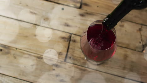 Composite-of-red-wine-being-poured-into-glass-on-wooden-surface