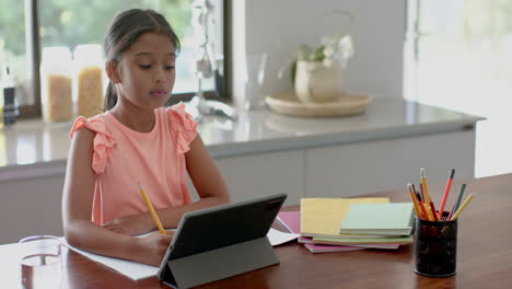 Focused-biracial-girl-having-elementary-school-class-on-tablet-in-kitchen,-copy-space,-slow-motion