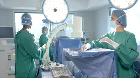 Diverse-female-and-male-surgeons-in-masks-preparing-operating-theatre-for-surgery,-slow-motion