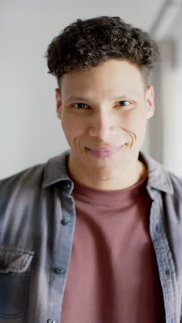 Vertical-video-of-portrait-of-happy-biracial-man-at-home,-in-slow-motion