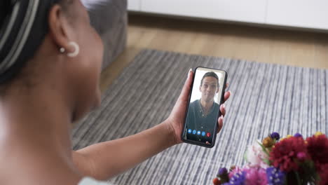 African-american-woman-holding-smartphone-with-biracial-man-on-screen