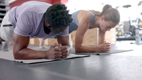 Fit-African-American-man-and-young-Caucasian-woman-exercising-at-the-gym