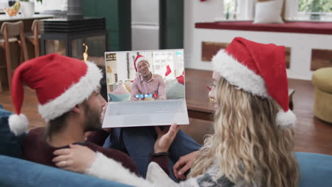 Happy-diverse-couple-and-senior-male-friend-having-christmas-laptop-video-call,-slow-motion