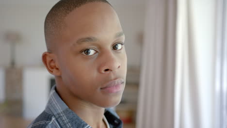 Portrait-of-thoughtful-african-american-male-teenager-with-short-hair-at-home,-slow-motion